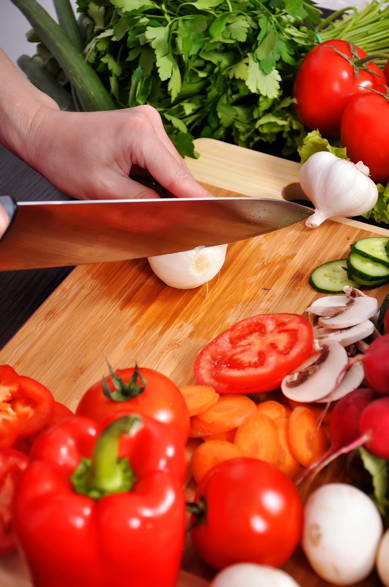 Hands chopping fresh produce on wooden board